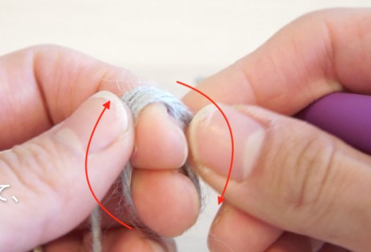 二重の輪で作り目を作る円の編み方を説明しています。左の人差し指と中指に、糸を下から上へ２回巻いている様子です。