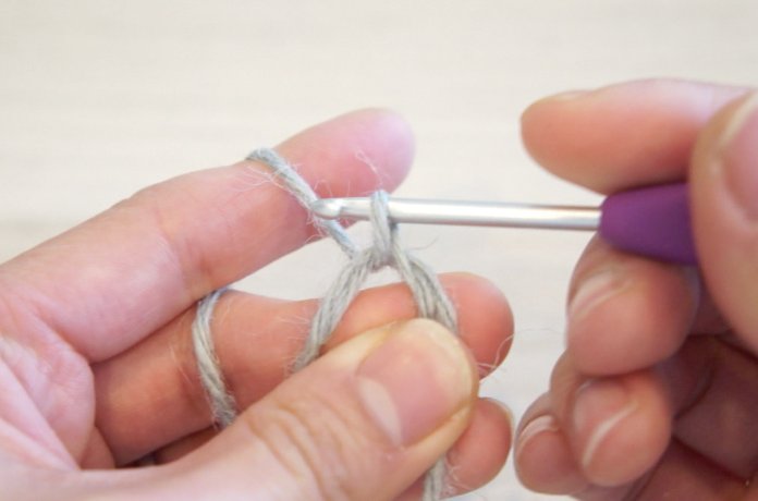二重の輪で作り目を作る円の編み方を説明しています。二重の輪にかぎ針を入れる糸を引き出す様子です。